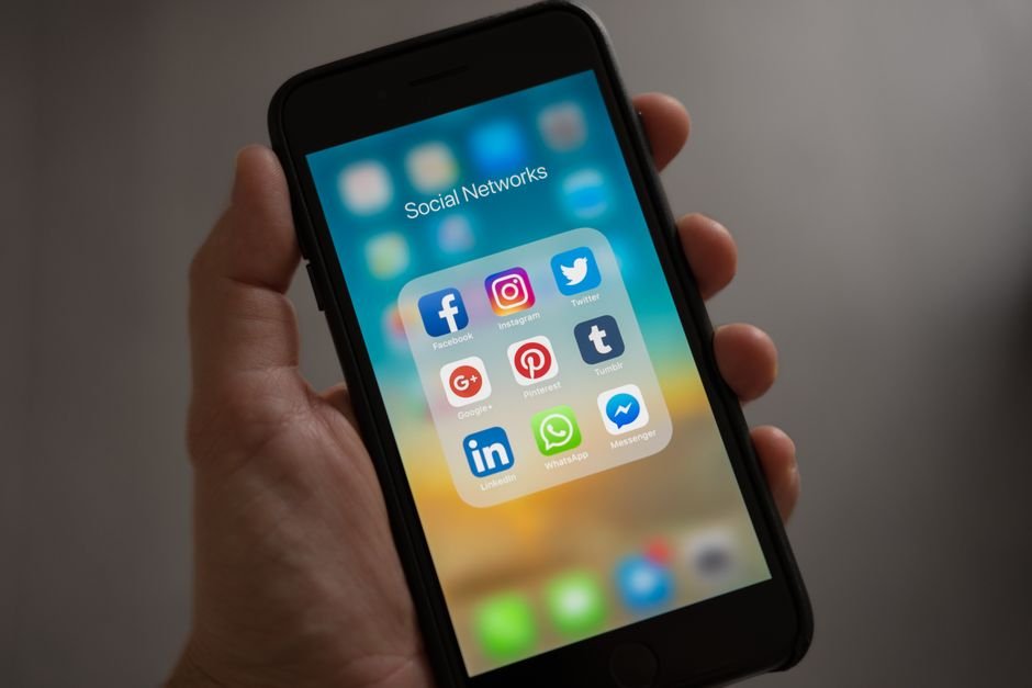 Personne tenant un smartphone avec des applications de réseaux sociaux